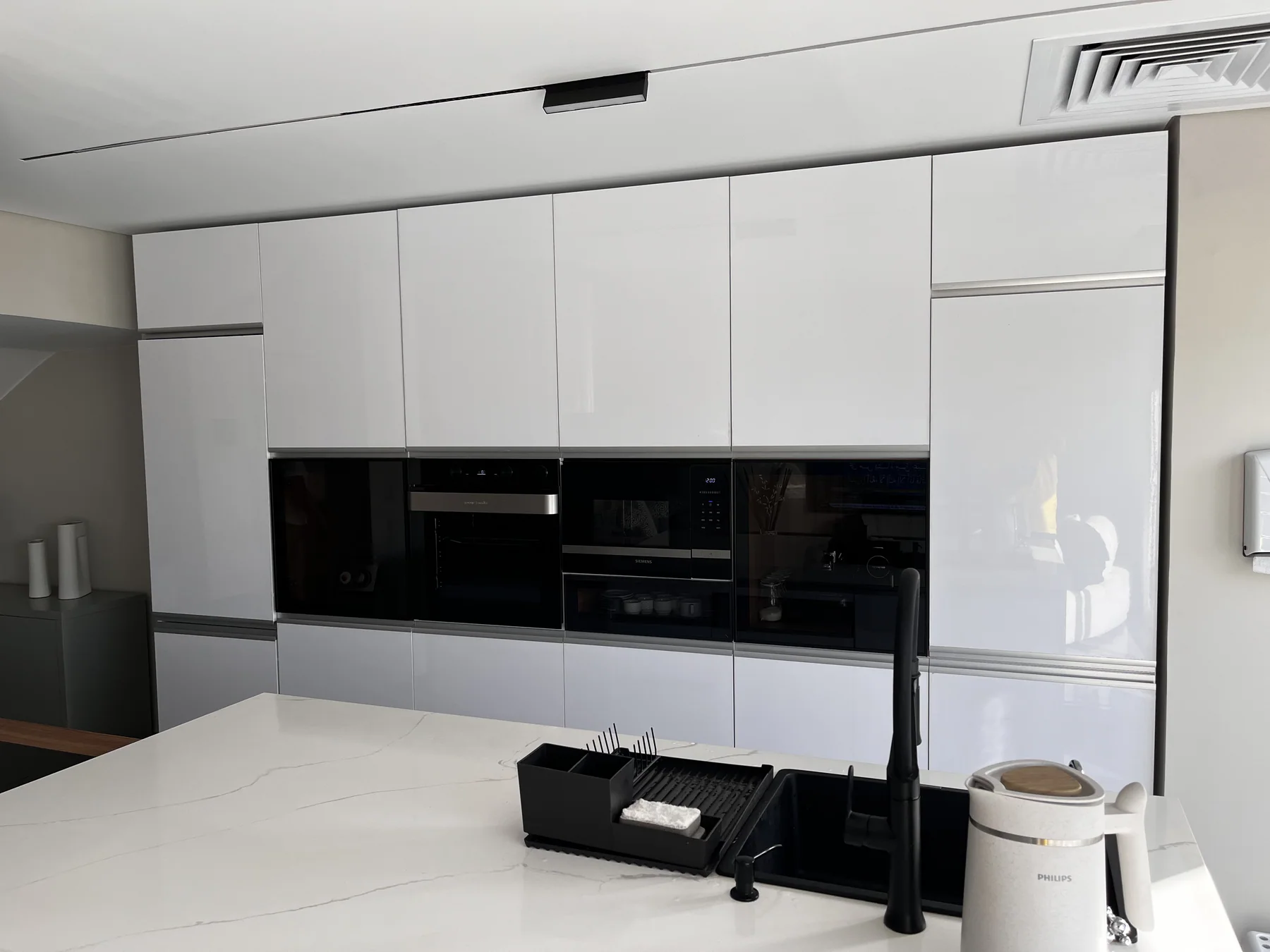 Full-height white kitchen cabinetry with black integrated appliances