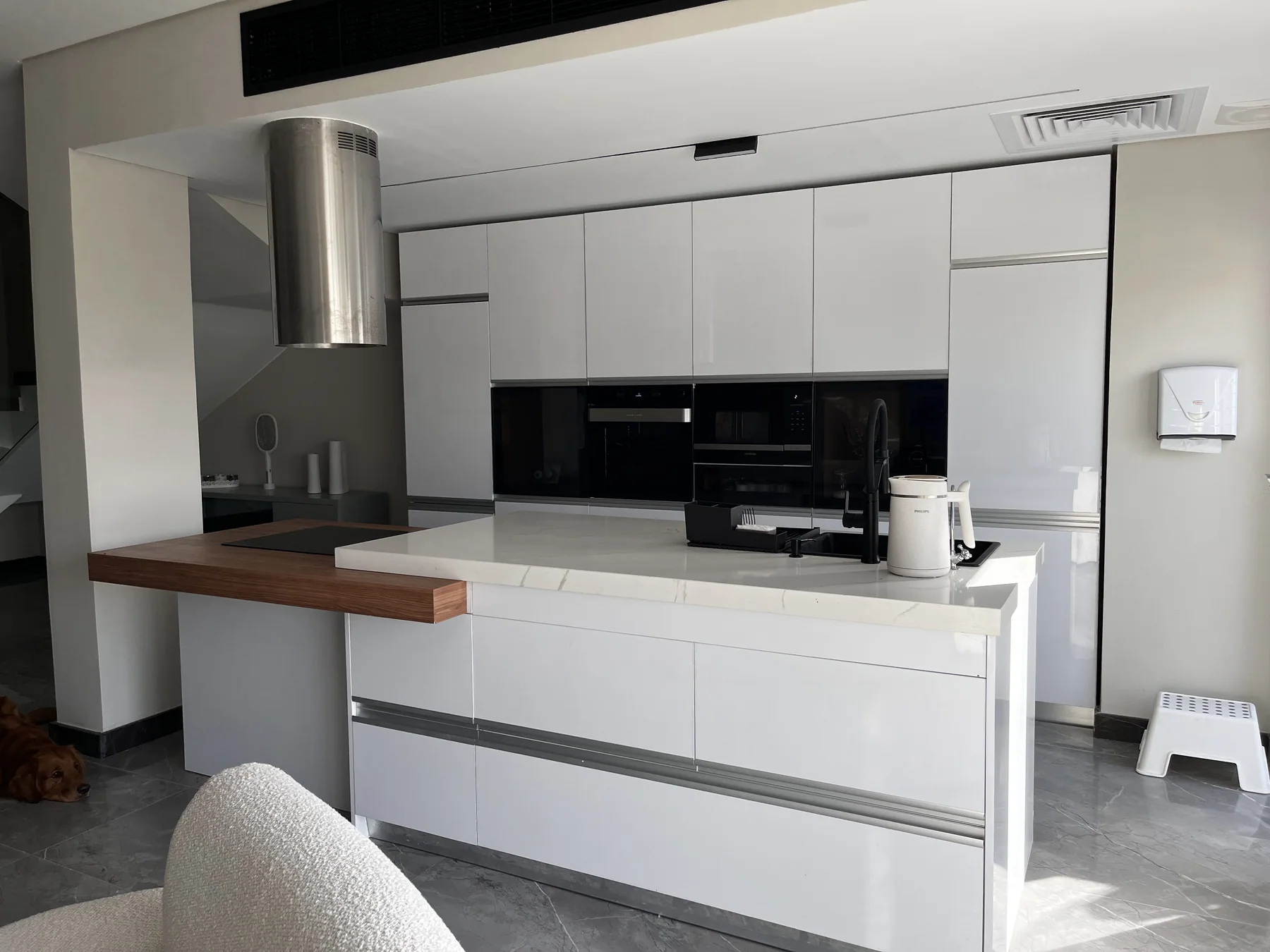 Glossy white cabinetry framing a walnut breakfast counter